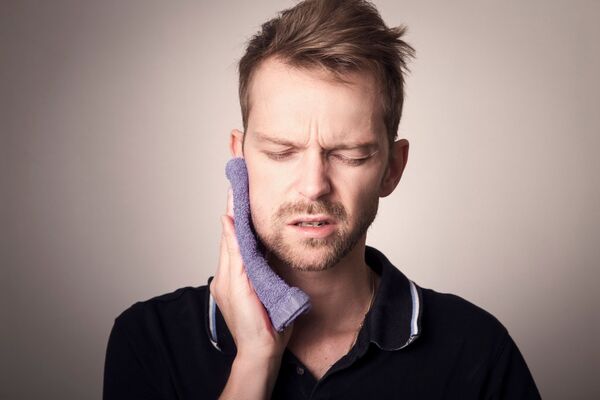 un jeune homme tient une serviette sur sa machoire qui lui fait mal