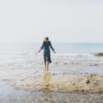 une jeune femme sur une plage face à la mer