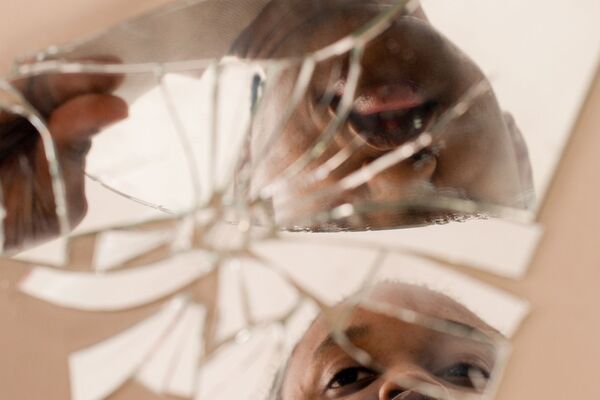une jeune fille se relfète dans un miroir brisé