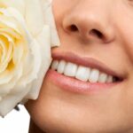 le sourire d'une jeune femme avec une rose blanche