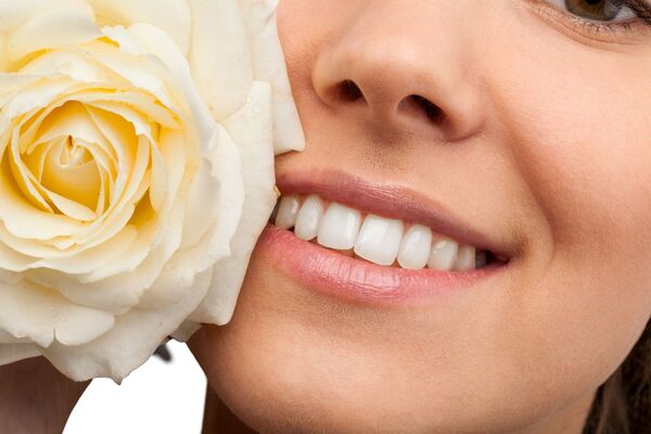 le sourire d'une jeune femme avec une rose blanche